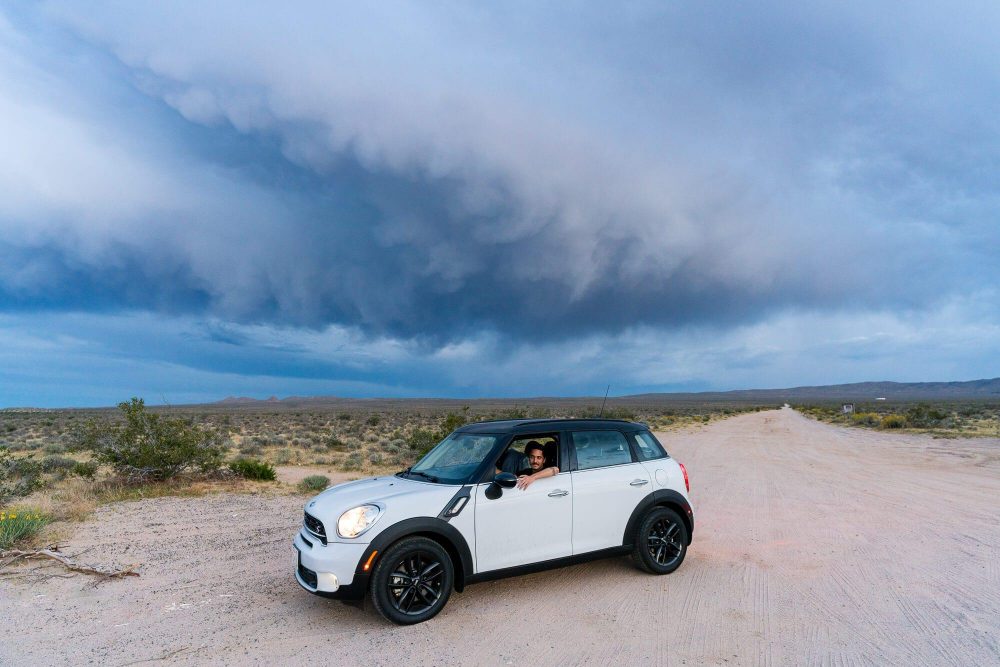 tyler minney sitting in the driver seat of white mini countryman under a storm cloud | photo by jake landon schwartz