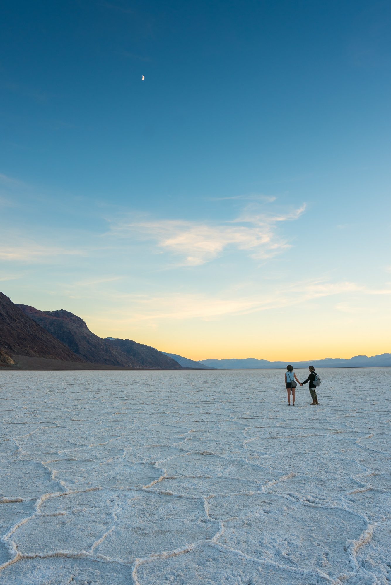 pj miles and joey ketterle hold hands and look up at the moon at badwater basin in death valley national park shot with sony a7rii | photo by jake landon schwartz